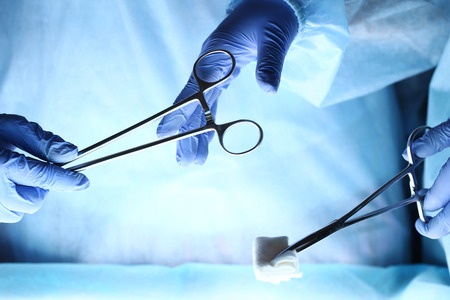chirurgien faisant passer un instrument à un autre médecin durant une opération