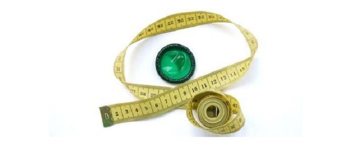 preservatif de couleur vert posé à coté d'un mètre de tailleur